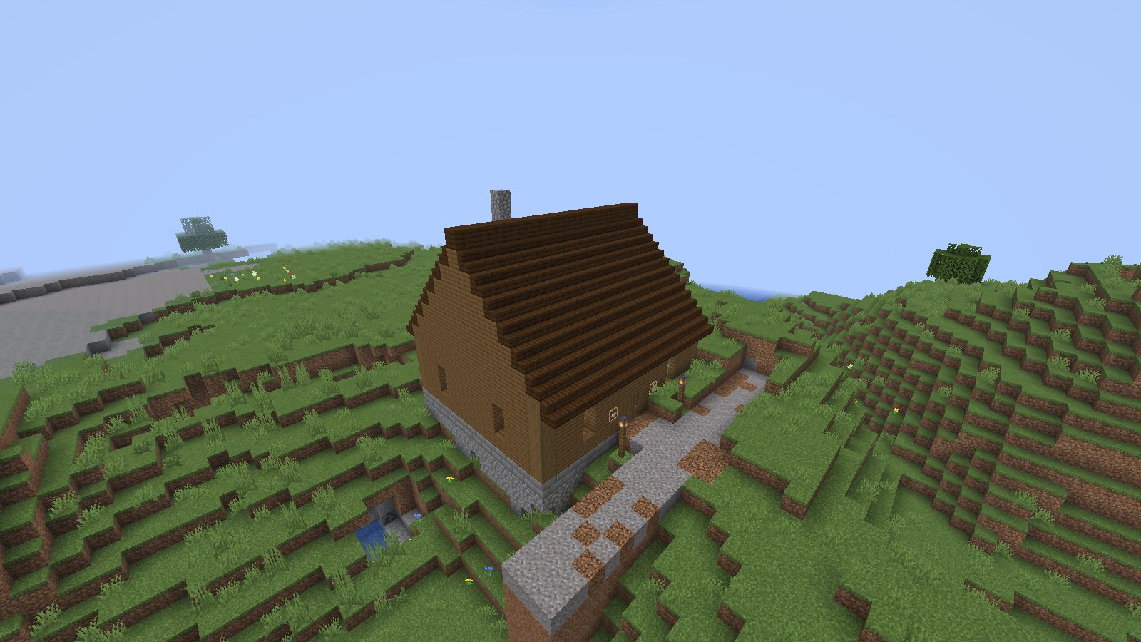 A spruce wayfarer inn with a steep roof and a stone chimney on a hillside, a gravel road leading to its door